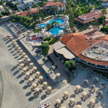 Vista aerea di un resort sulla spiaggia con piscine e ombrelloni.