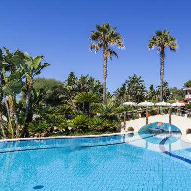 Piscina con palme e lettini in un resort tropicale.