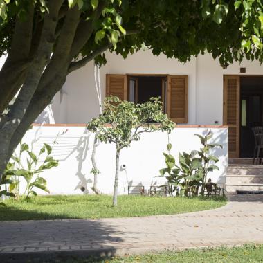 Giardino con veranda, piante e sedie all'aperto.