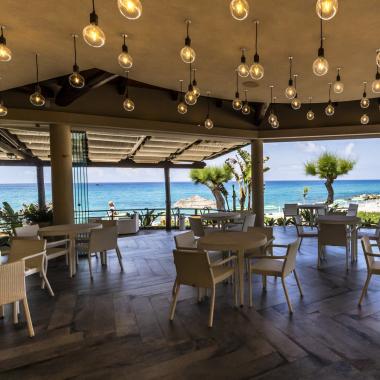 Ristorante con vista mare, arredamento moderno e lampade sospese.