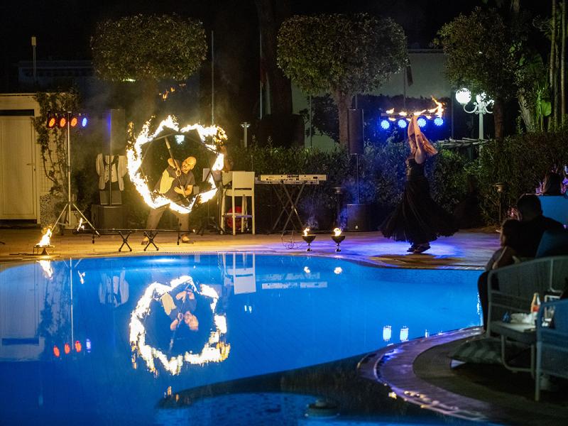 Spettacolo di fuoco serale vicino alla piscina con pubblico.