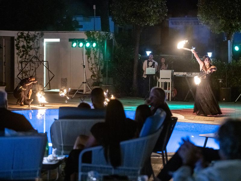 Spettacolo di fuoco a bordo piscina con pubblico attento.