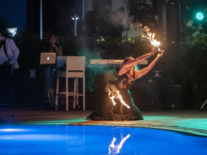 Artista esegue spettacolo di fuoco vicino alla piscina di notte.