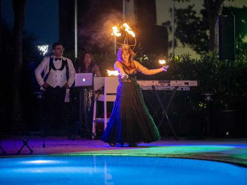 Artista esegue spettacolo di fuoco vicino alla piscina di notte.