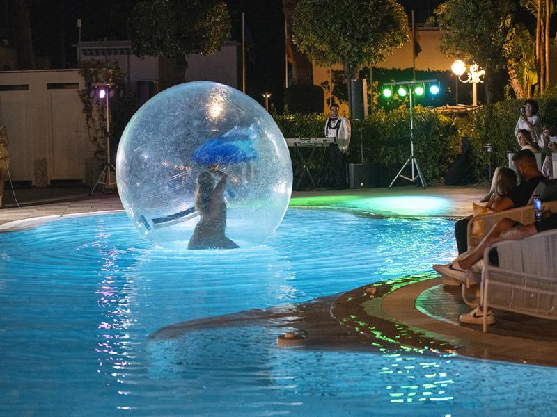 Spettacolo in piscina con artista in bolla trasparente.