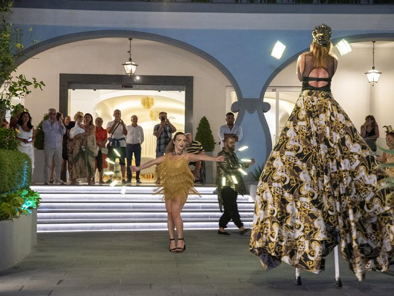 Performance serale con danzatori e trampolieri davanti a un pubblico.