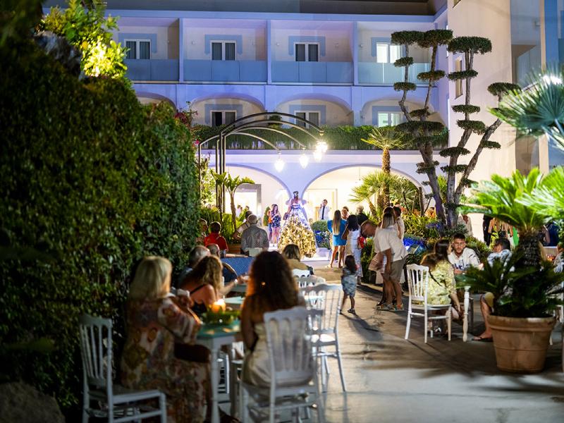 Serata estiva in hotel con persone che cenano all'aperto.