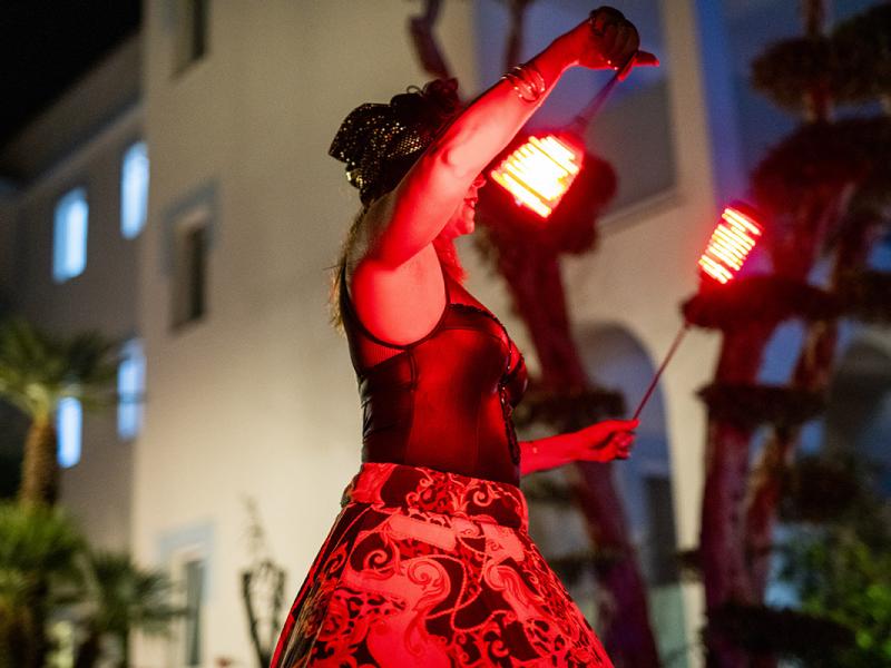 Artista di strada con luci LED rosse in un'esibizione notturna.