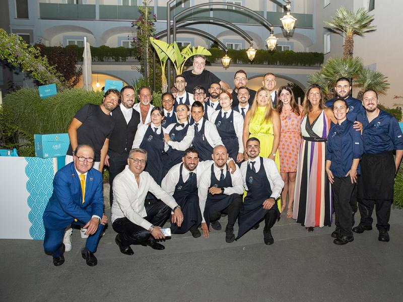 Gruppo di persone sorridenti in un evento all'aperto.