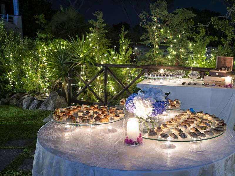 Outdoor table with pastries and light decorations.
