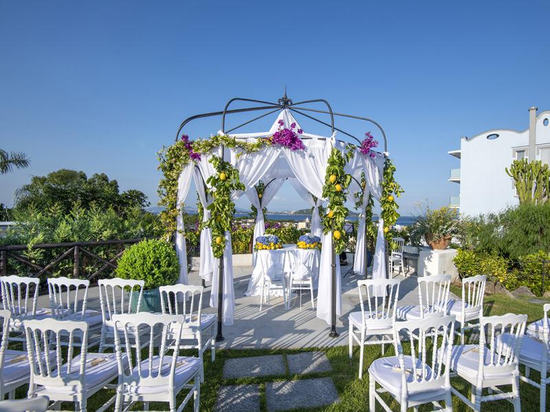 Decorated gazebo for outdoor ceremony with flowers and lemons.