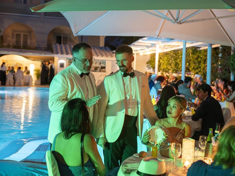 Elegant poolside dinner with guests in formal attire.