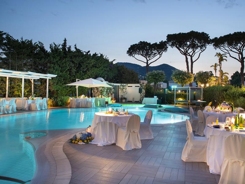 Elegant poolside dinner with soft lighting and set tables.