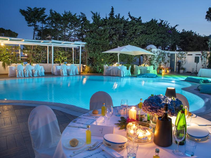 Elegant poolside dinner with candles and floral decorations.