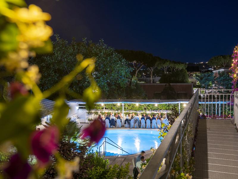 Outdoor dinner by the pool with night lights.