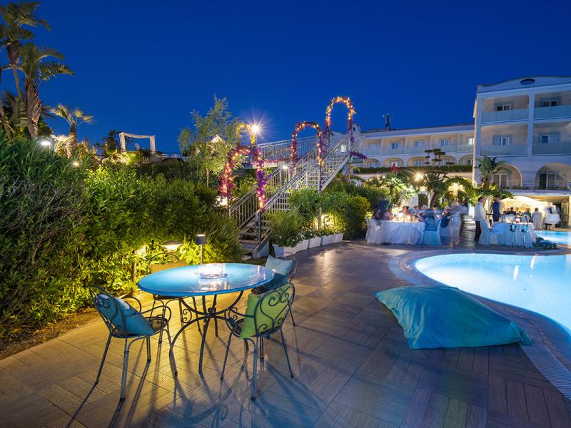 Evening-lit pool with tables and floral decorations.
