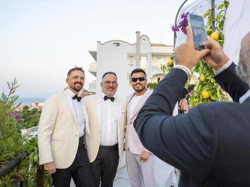 Elegant people pose for a photo at an outdoor event.