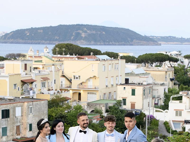 Elegant group poses for a photo on a terrace with sea view.