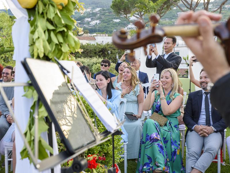 Smiling guests at an outdoor event with live music.
