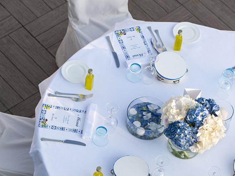Elegant table with blue and white flowers, menus, and oil bottles.