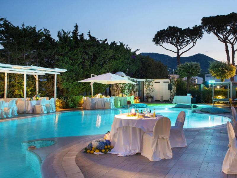 Elegant outdoor dinner by the pool with soft lights at sunset.