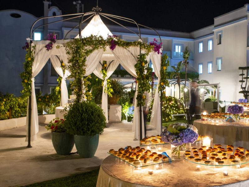 Elegant evening outdoor event with decorated gazebo and buffet.