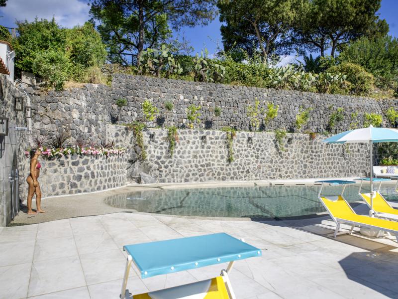 Piscina all'aperto con lettini gialli e ombrelloni azzurri.