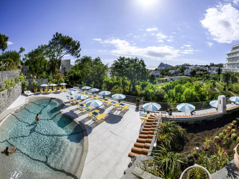 Piscina all'aperto con ombrelloni e vista panoramica.