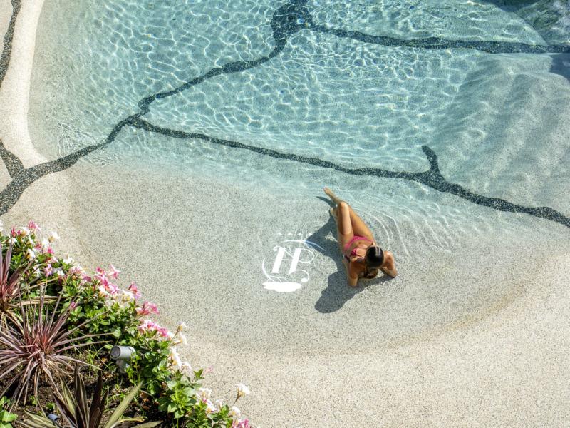 Donna in piscina, relax e sole, circondata da fiori.
