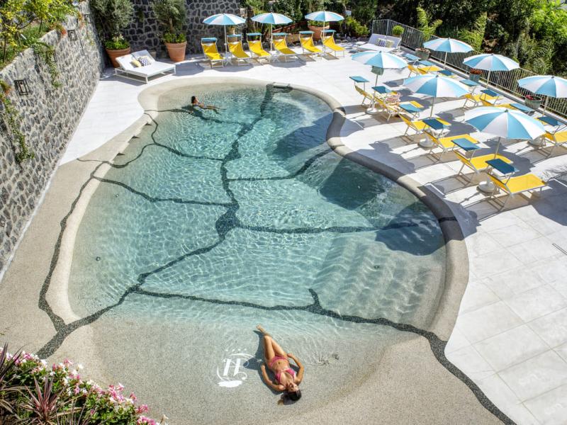 Piscina con lettini e ombrelloni colorati in un ambiente soleggiato.
