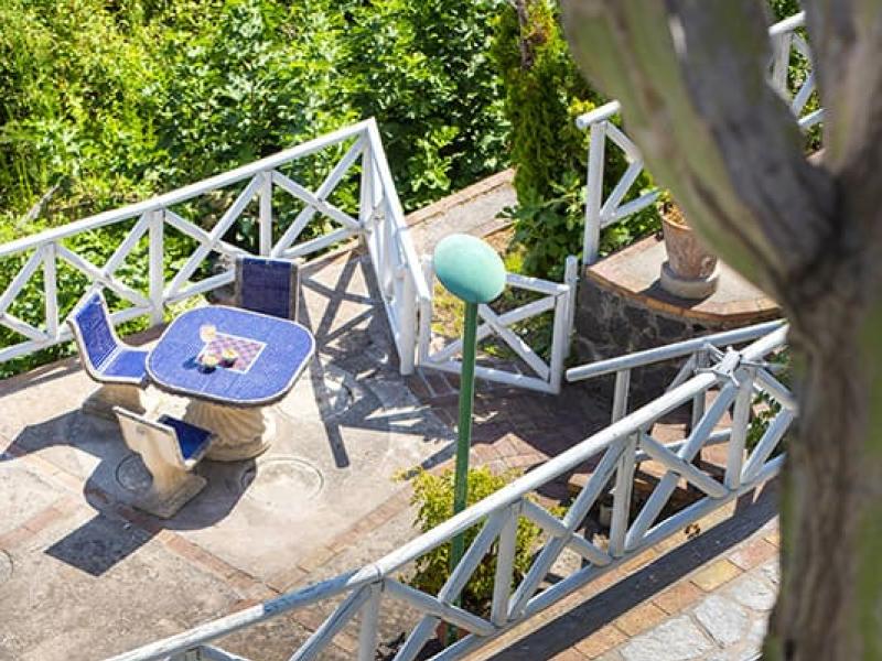 Donna in piscina, terrazza con tavolo e sedie, ambiente verde.