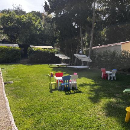 Giardino soleggiato con giochi colorati per bambini, atmosfera di gioia e serenità.