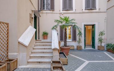 Cortile interno con piante in vaso e scale in marmo.