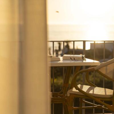 Golden sunset on balcony with chair, books, and glasses.