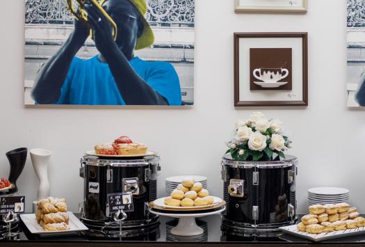 Elegantes Buffet mit Desserts auf Trommeln, bunte Kunst und musikalische Atmosphäre.