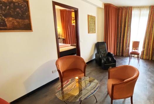 Elegantes Zimmer mit Sesseln, Tisch, bunten Vorhängen und Massagesessel.