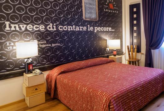 Gemütliches Zimmer mit Doppelbett und Wein-Thema Dekoration.