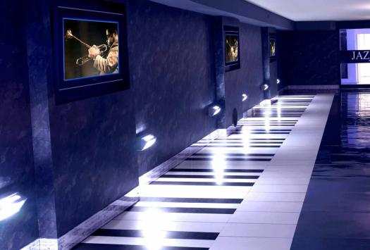 Jazz-Korridor mit Klaviertastenboden, sanfter Beleuchtung und bunten Sofas.