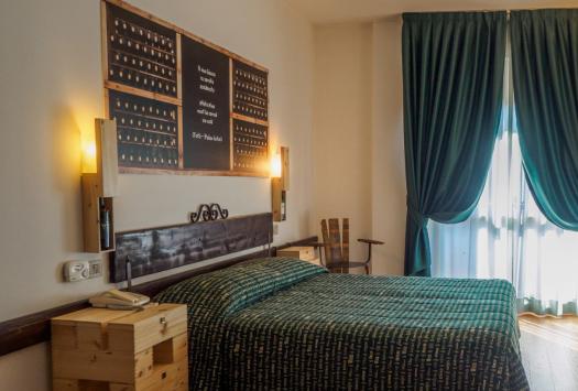 Gemütliches Zimmer mit Bett, grünen Vorhängen und rustikalen Dekorationen.
