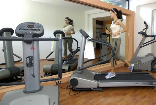 Frau läuft auf Laufband im hellen Fitnessstudio, energetische und motivierende Atmosphäre.