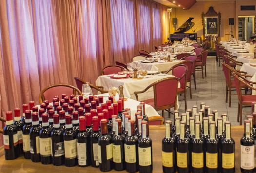 Elegantes Restaurant mit gedeckten Tischen und Weinflaschen, warme und einladende Atmosphäre.
