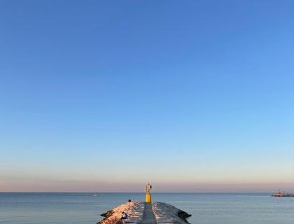 Molo al tramonto, luce dorata, mare calmo, cielo limpido, pace e serenità.