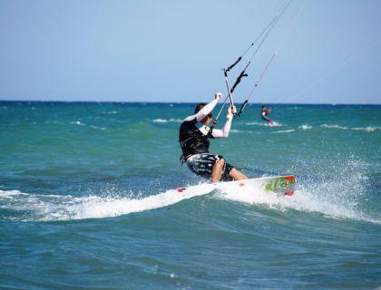Kitesurfer cavalca onde azzurre, vento in faccia, libertà e adrenalina.
