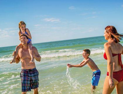 Famiglia felice gioca e ride in mare sotto il sole estivo.