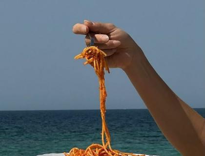 Spaghetti al pomodoro, mare sullo sfondo, atmosfera di vacanza e relax.