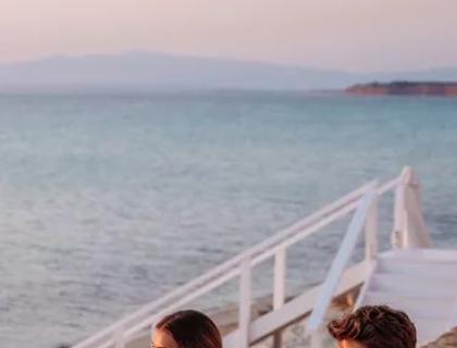 Famiglia felice al tramonto, abbracciati vicino al mare, atmosfera serena e amorevole.