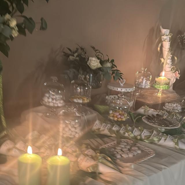 Tavolo elegante con candele verdi e dolci, atmosfera calda e accogliente.