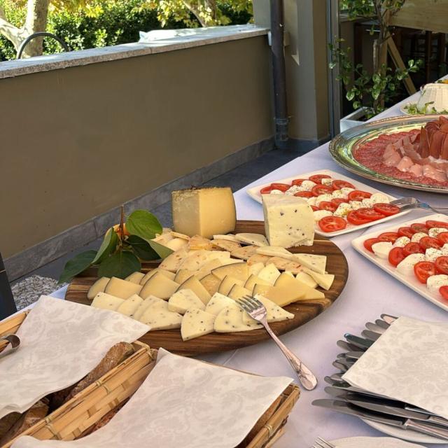 Buffet colorato con formaggi, salumi e insalate, atmosfera conviviale all'aperto.