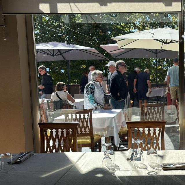 Gruppo di persone felici sotto ombrelloni, atmosfera conviviale e luminosa.