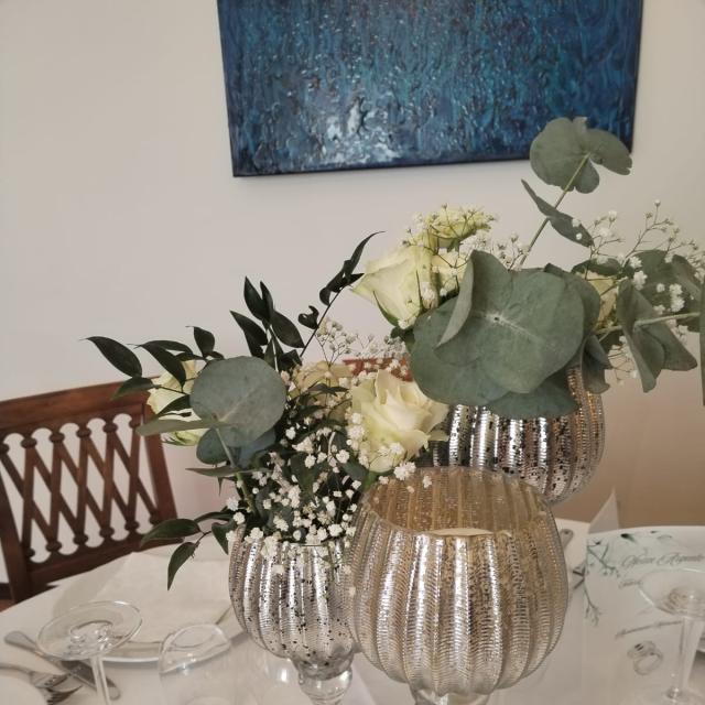 Elegante centrotavola con fiori bianchi e calici argentati su tavola raffinata.